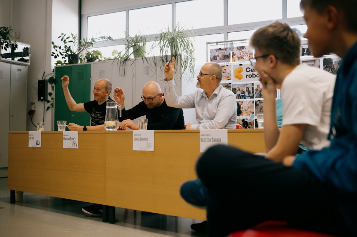 Members of the jury raising their hands during the Škrábej, kotě! competition final at Centrum robotiky in Plzeň