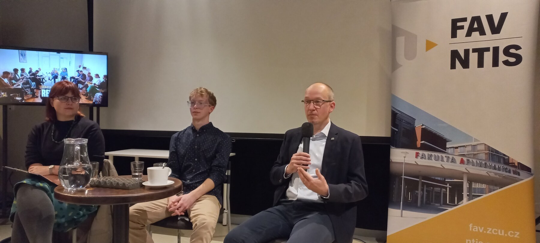 Jan Švec mluví do ručního mikrofonu během Debaty s Respektem v Moving Station